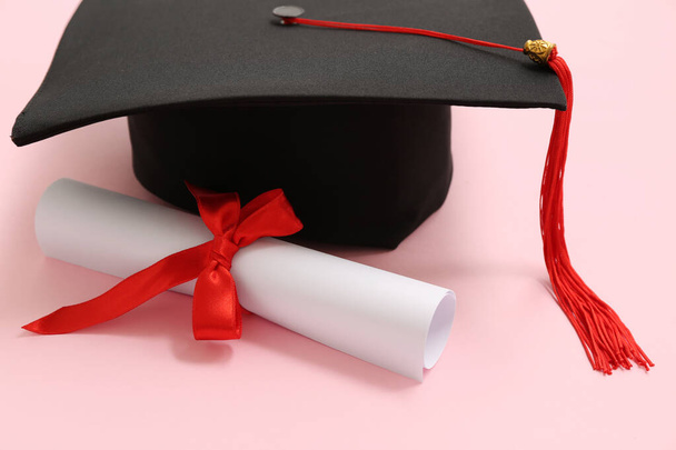 Afstudeerhoed en diploma op roze achtergrond - Foto, afbeelding