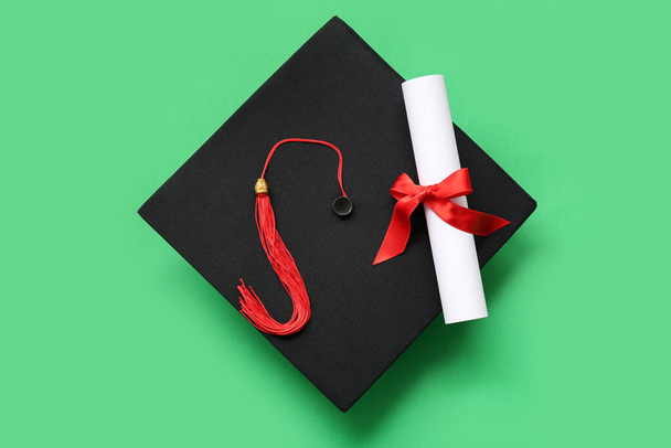 Graduation hat and diploma on green background - Photo, Image