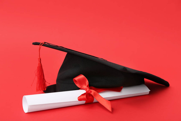 Mortierbord en diploma op rode achtergrond - Foto, afbeelding