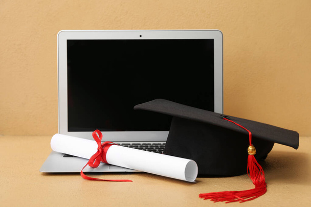 ブラウンの背景に卒業証書とモダンなノートパソコンを搭載したモーターボード - 写真・画像