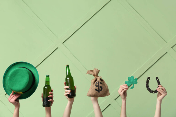 Female hands holding beer and party decor for St. Patrick's Day celebration on green background - Photo, Image