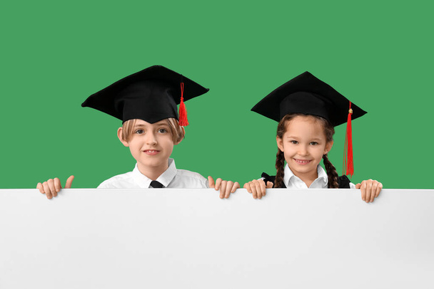 グリーンの背景に白いポスターが付いている卒業式帽子の小さな子供. 学年終了について - 写真・画像