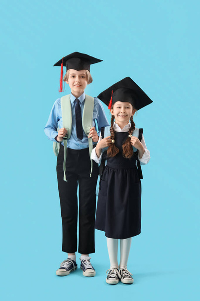Μικρά παιδιά με καπέλα αποφοίτησης σε μπλε φόντο. Τέλος του σχολικού έτους - Φωτογραφία, εικόνα