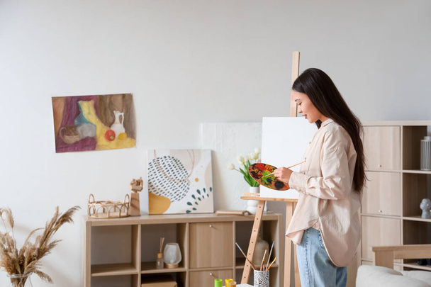 Female Asian artist drawing on easel at home - Photo, Image