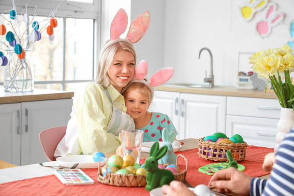 Madre feliz con su hijita abrazándose en la cocina el día de Pascua - Foto, Imagen