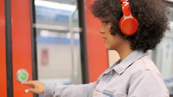 Lassított felvétel egy transznemű nőről, amint beszáll egy metrókocsiba, miközben zenét hallgat fejhallgatóval - Felvétel, videó
