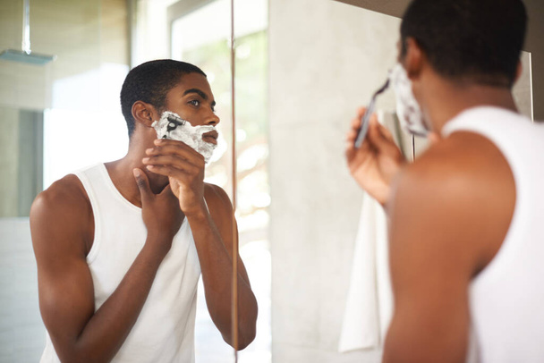 Specchio, rasatura o toelettatura e uomo nero in bagno di casa con rasoio per la depilazione mattutina. Viso, cura della pelle e riflessione dei giovani con schiuma per radersi la barba per igiene di routine. - Foto, immagini