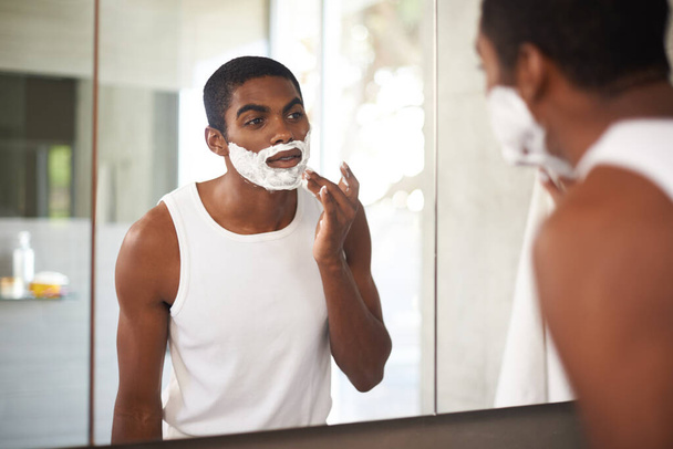 Чорний чоловік, дзеркало та вершки для гоління на обличчі у ванній кімнаті для догляду за шкірою або ранковою рутиною. Відбиття, борода і людина застосовують піну для прибирання, здоров'я і видалення волосся для гігієни в домашніх умовах. - Фото, зображення