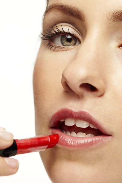 woman putting on red lipstick - Foto, afbeelding