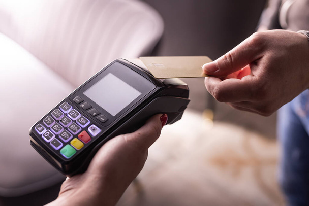 NFC kredi kartı ödemesi. NFC teknolojisiyle kredi kartıyla ödeme yapan bir kadın. Kablosuz para transferi. Kart makinesi erkek eliyle güneş ışığı arkaplanında - Fotoğraf, Görsel
