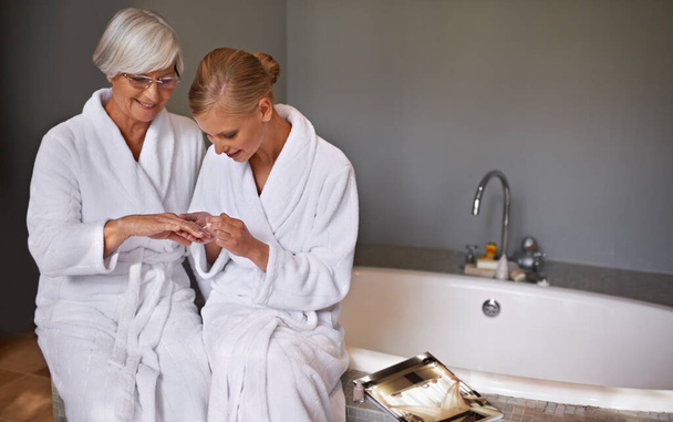 Mother, spa and manicure with daughter, bath and senior woman for bonding and relaxation. Parent, robe and nail polish with cosmetics, guidance and support with beauty treatment or pamper and glasses. - Φωτογραφία, εικόνα
