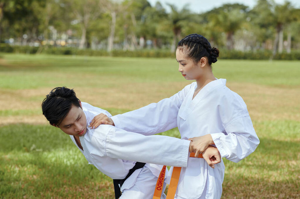 Taekwondo athlete attacking her opponent when fighting outdoors - Photo, Image
