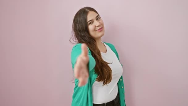 Schöne, erfolgreiche hispanische Frau lächelt, steht über isoliertem rosa Hintergrund und reicht selbstbewusst zur Begrüßung einen freundlichen Händedruck - ein Symbol erfolgreicher beruflicher Partnerschaft. - Filmmaterial, Video