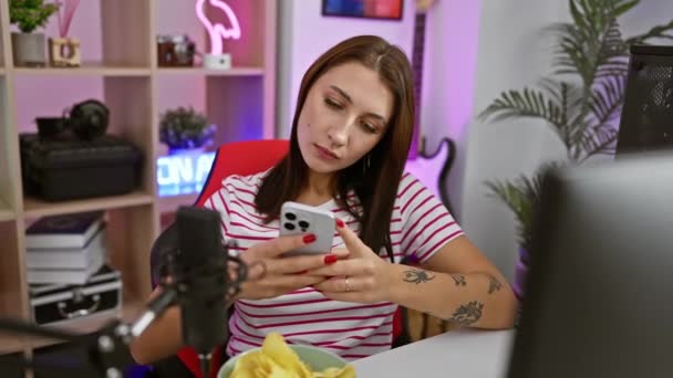 Sebevědomá mladá brunetka používá smartphone v herně, ukazuje prstem na kameru, dává vám vážný pohled, signalizuje, že jste její vyvolený. - Záběry, video