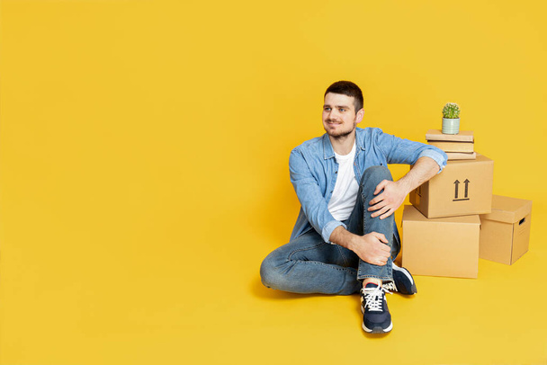 Un hombre con cajas, sobre un fondo amarillo, el concepto de movimiento. - Foto, Imagen