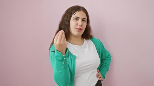 Mooie jonge Spaanse vrouw, vol vertrouwen uitdrukken met een Italiaans handgebaar, staat geïsoleerd over een roze achtergrond - Video