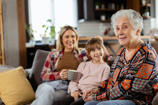 3世代の女性が快適なリビングルームのソファーで笑いと会話を楽しむ - 写真・画像