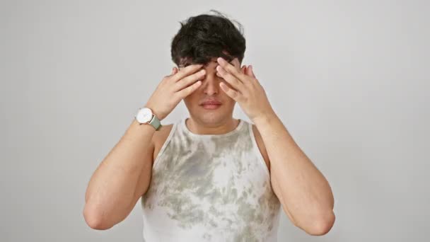Young man, stressed and worn-out, rubbing tired eyes due to fatigue. sleepy expression echoes headache and vision problems. isolated against white background. - Footage, Video