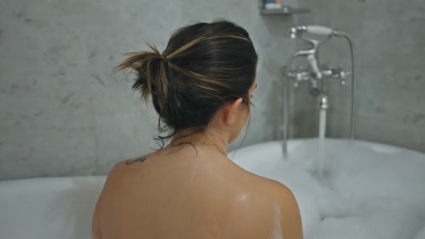 Een jonge vrouw ontspannen alleen in een huis badkamer met schuim, presentatie van rust en zelfzorg. - Video