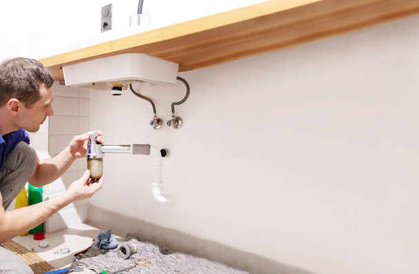 Caucasian male plumber fixing a sink in the bathroom - Photo, Image