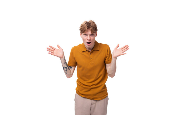 young fashionable student man with short red hair dressed in a yellow t-shirt is actively gesturing. - Photo, Image