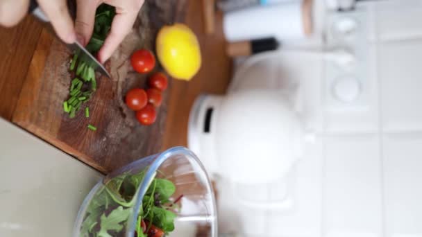 Culinary concept, preparation ingredients for homemade food. Vertical shot an unrecognizable woman cooking a meal, tears lettuce into a salad bowl at kitchen indoors. Vegetables on the table - Footage, Video