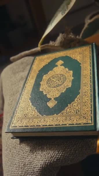 Keine vertikalen Filmaufnahmen des heiligen Buches Koran in dunkelgrünem, festem Einband mit goldenen Ornamenten, die zu Hause auf dem Couchtisch liegen - Filmmaterial, Video