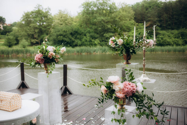 Hermoso arco de boda redondo decorado con flores y vegetación cerca de lago o río al aire libre, espacio de copia. Decoraciones para la ceremonia de boda al aire libre. Foto de alta calidad - Foto, Imagen