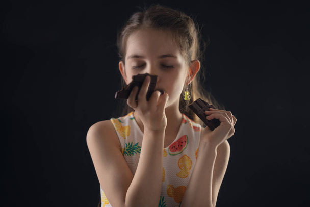Chocolate and pretty hungry little woman portrait. Beautiful girl ready to eat chocolate bar. - Photo, Image