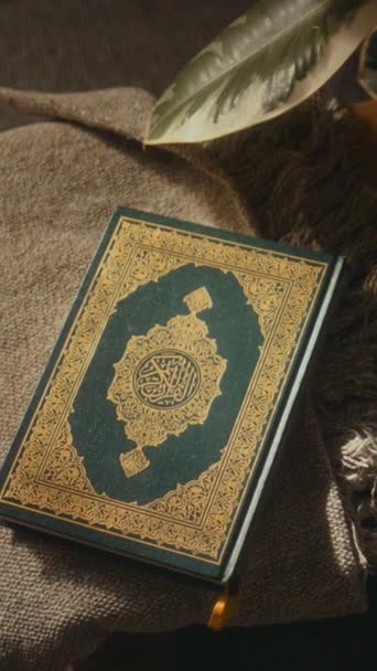 Keine Menschen flach legen vertikale Aufnahmen des heiligen gesegneten Buch des Qur 'an in grünem Hardcover und dekoriert mit goldenen Ornamenten liegen auf kleinem Tisch im Haus - Filmmaterial, Video
