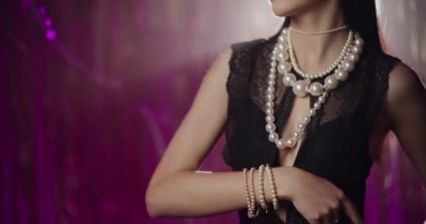 Attraente seducente giovane donna in gioielli di perle e occhiali da sole toccare corpo e viso di fronte alla decorazione - Filmati, video