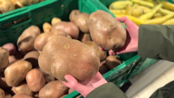 Frau zeigt zwei baltische Rosenkartoffeln, kauft im Supermarkt ein, kauft gesunde Lebensmittel, Konzept von Lebensmittelgeschäften. Hochwertiges 4k Filmmaterial. - Filmmaterial, Video