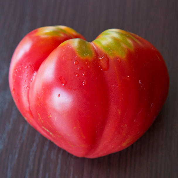 Red tomato in shape of heart on brown background - Fotografie, Obrázek