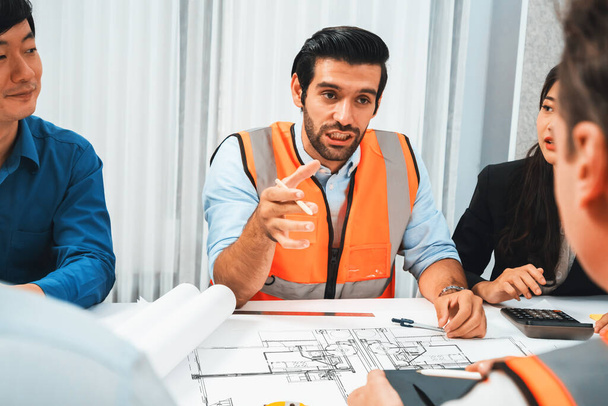 Diverse group of civil engineer and client working together on architectural project, reviewing construction plan and building blueprint at meeting table. Prudent - Photo, Image