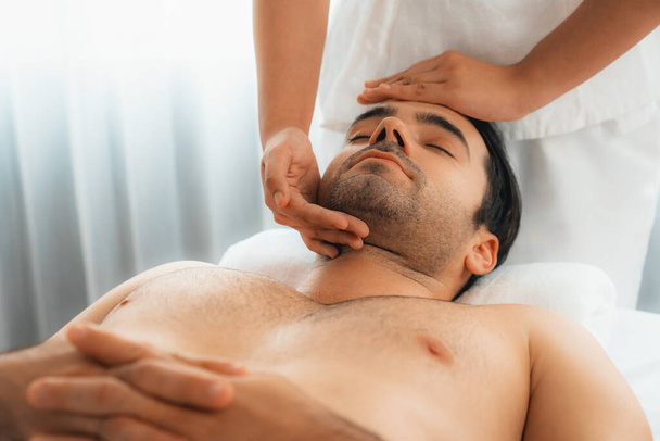 Uomo caucasico godendo rilassante anti-stress massaggio alla testa e coccole bellezza del viso svago della pelle in dayspa luce moderna ambiente al resort di lusso o salone spa dell'hotel. Silenzioso - Foto, immagini
