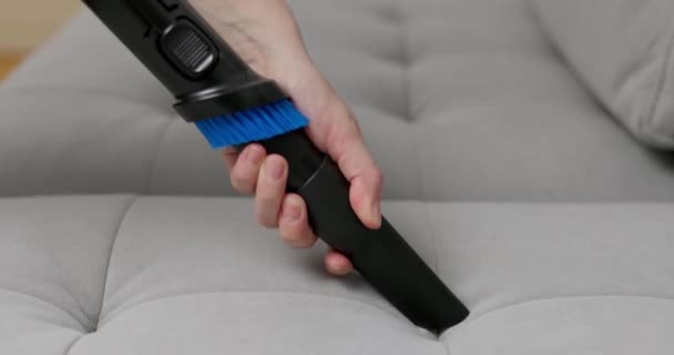 Close-up van een persoon hand met behulp van een borstel bevestiging op een stofzuiger voor een effectieve sofa reiniging. Hoge kwaliteit 4k beeldmateriaal - Video