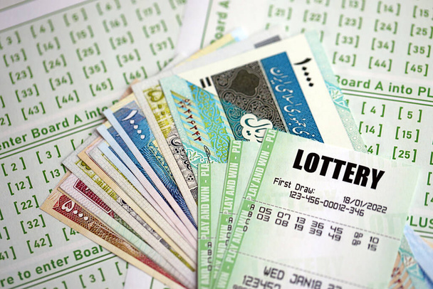 Зеленые лотерейные билеты и счета за иранские деньги на пустом месте с номерами для игры в лотерею крупным планом - Фото, изображение