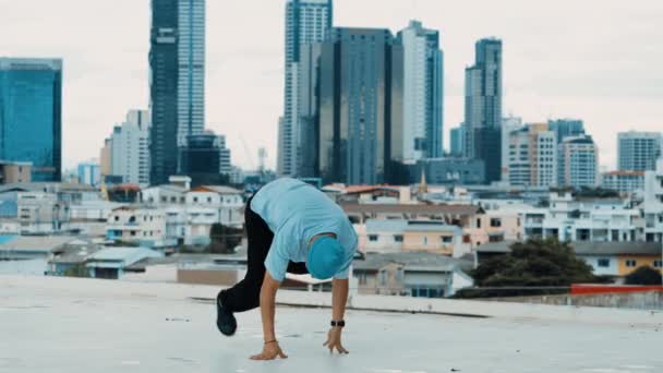 Profesjonalny biały B-boy tancerz ćwiczący taniec uliczny na dachu z miastem lub miastem. Motion shot młodego człowieka wykonującego taniec uliczny poprzez zamrożenie pozycji. Odkryty sport 2024. hiphop. - Materiał filmowy, wideo