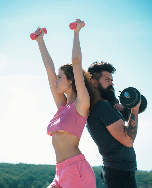 Sporty woman in sexy pink sportswear. Sportive fitness couple, bearded man and sexy woman working out outdoors, sportive couple training with dumbbells, muscular coupl outdoor - Fotoğraf, Görsel