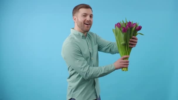 Ο άνθρωπος χορεύει με ένα μπουκέτο λουλούδια σε μπλε φόντο - Πλάνα, βίντεο