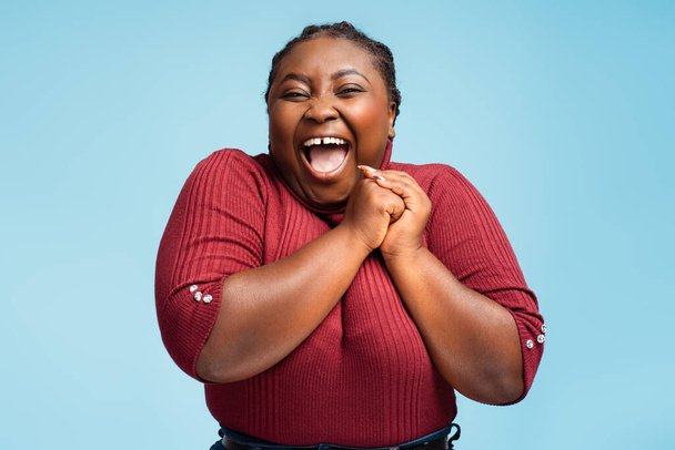 Beautiful, overjoyed African American woman rejoicing with open mouth looking at camera standing isolated on blue background. Concept of celebration, success - Fotoğraf, Görsel