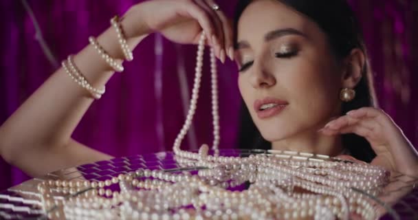 Gros plan de séduisante jeune femme avec collier de perles appuyé sur une table en verre - Séquence, vidéo