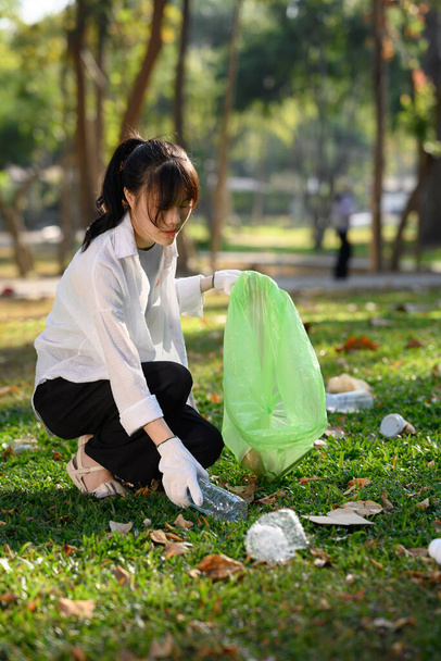 Shot of young lady collecting plastic bottles, cleaning up nature. Charity and ecology concept. - Foto, Imagen