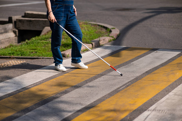 Close-up of the legs of a blind woman crossing the road at a crosswalk with a cane - Foto, Imagem