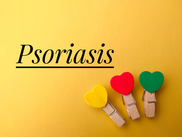 Top view colored wooden clips with text Psoriasis on yellow background. - Photo, Image