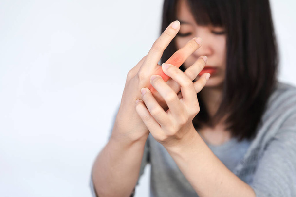 Женщина испытывает боль в костяшках пальцев или кисти рук от интенсивного использования на белом фоне. - Фото, изображение