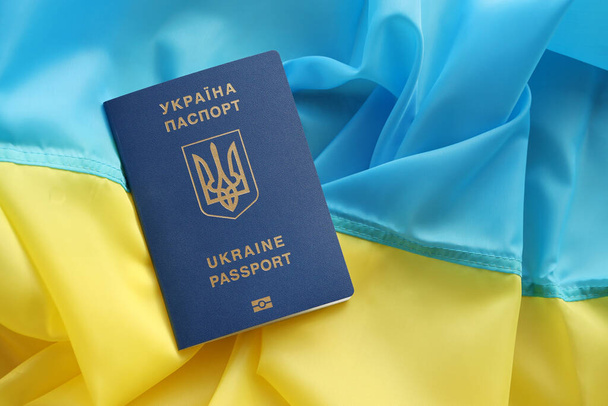 Jeden ukraiński paszport biometryczny na składanej fladze falującej Ukrainy kraju zbliżyć - Zdjęcie, obraz