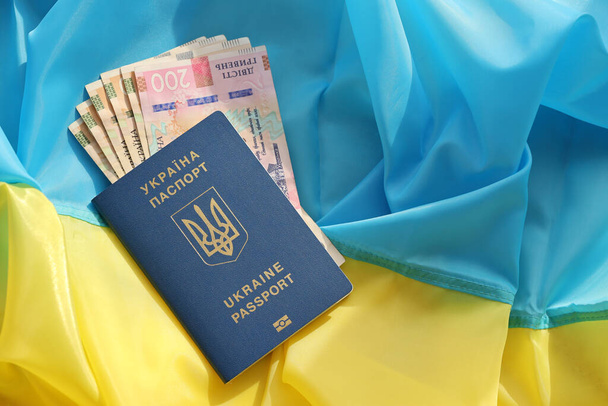 Jeden ukraiński paszport biometryczny i hrywna UAH banknoty na składanej flagi falujące Ukrainy kraju zbliżyć - Zdjęcie, obraz