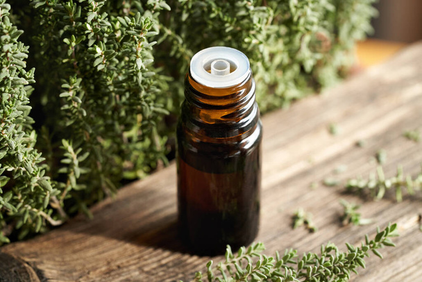 Una bottiglia di olio essenziale di aromaterapia con ramoscelli di timo freschi su un tavolo - Foto, immagini