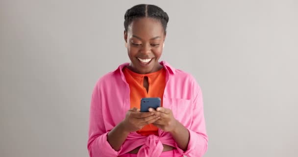 Wow, wiadomości i podekscytowana czarna kobieta z telefonem w studio na konkurs online daveaway na szarym tle. Tak, smartfon i szczęśliwa modelka z powiadomieniem o zgłoszeniu zwycięzcy lub nagrody. - Materiał filmowy, wideo